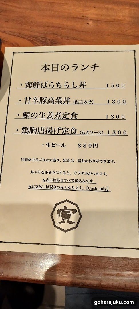 A printed lunch menu on a wooden table, featuring Japanese dishes with prices in yen.