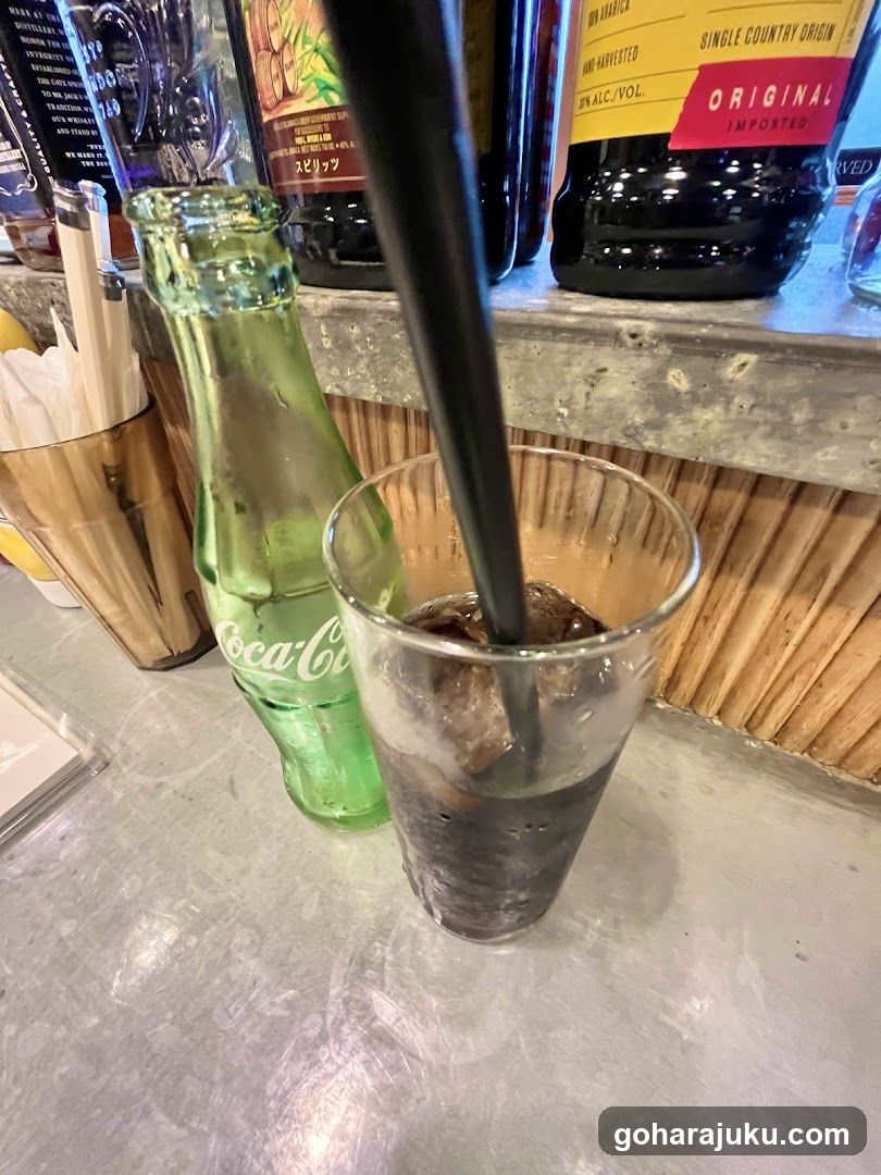 Coca-Cola bottle and glass with ice on counter