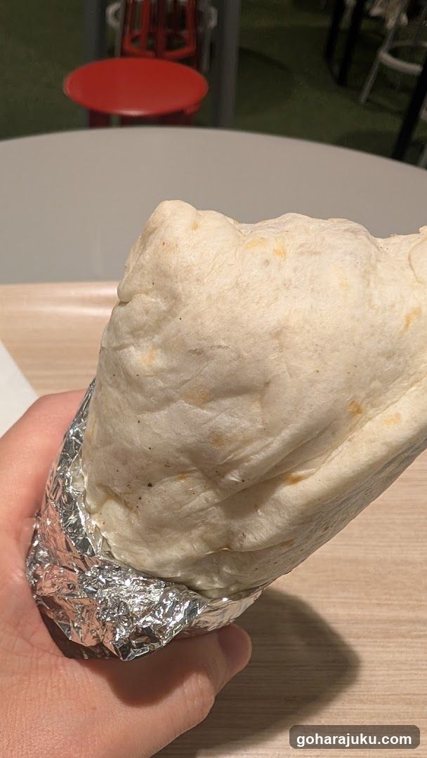 Hand holding a foil-wrapped burrito