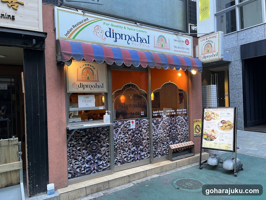 The image shows the exterior of Dipmahal, an Indian restaurant with a colorful striped awning and ornate wooden carvings on the lower facade. The signage includes 'Indian Restaurant' and 'For Quality & Spice Lovers'. A menu board is visible outside.