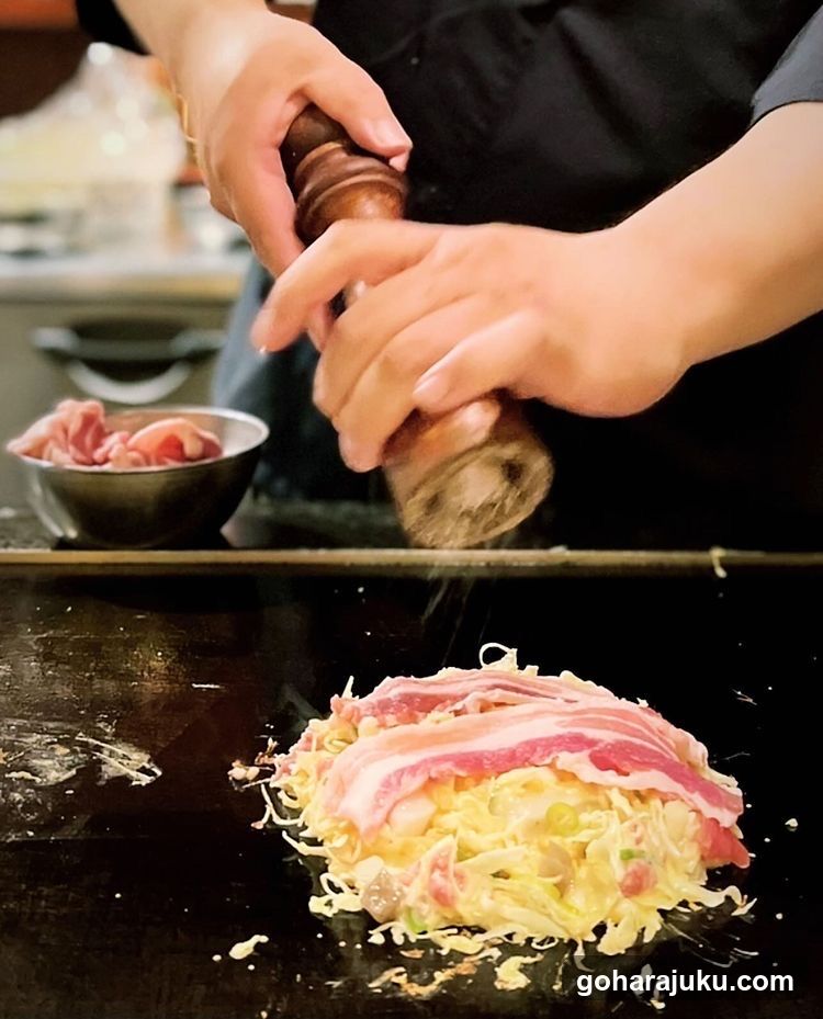 Chef Seasoning a Dish on Teppan