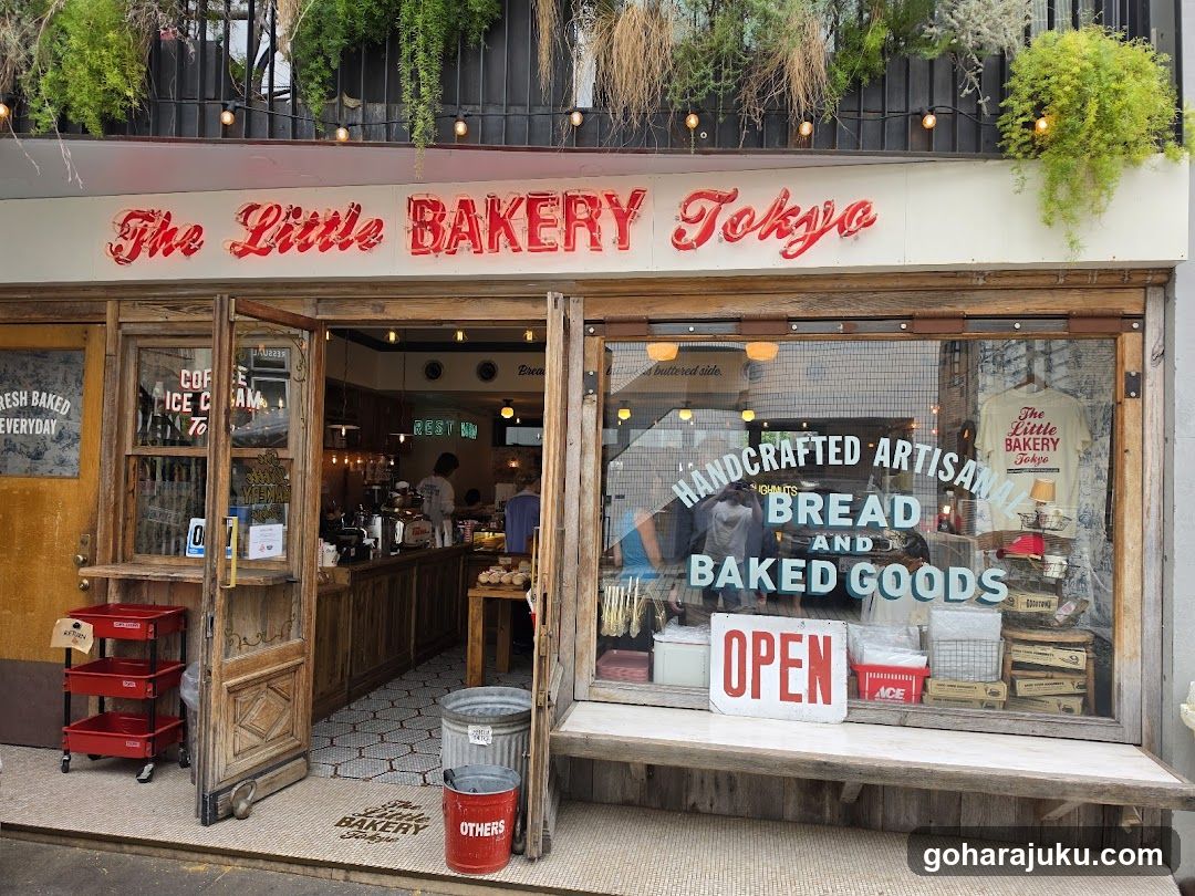 Exterior of The Little Bakery Tokyo storefront with visible signage, open wooden doors, and window displays featuring baked goods and an 'OPEN' sign.