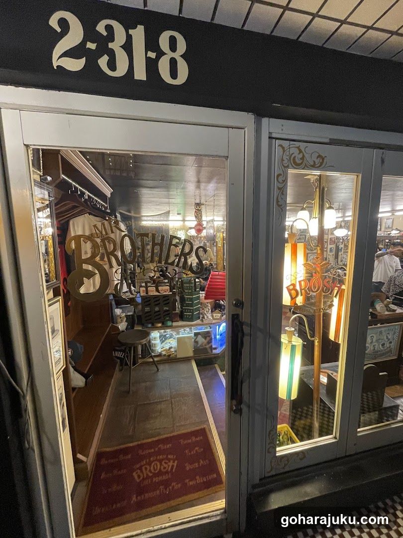 Exterior view of a bar entrance with '2-31-8' sign above door, glass doors showing interior decor including vintage lamps and 'BROSH' signage inside.