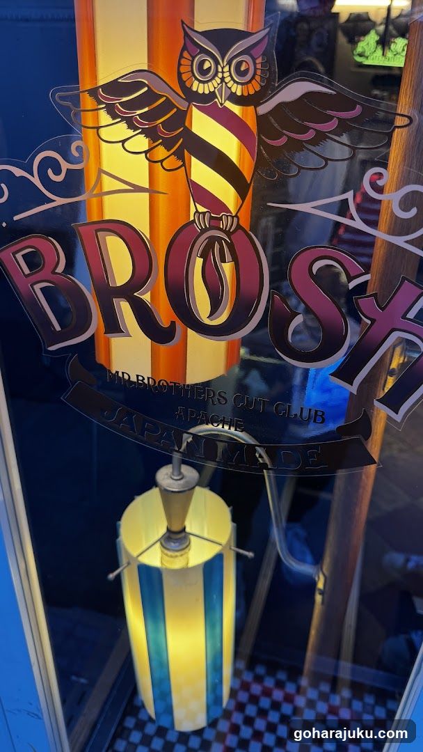A close-up view of the glass door entrance to a barbershop named 'BROSH'. The shop features a distinctive logo with an owl perched on a barber pole, and signage indicating it is a 'GUT CLUB' located in Japan.