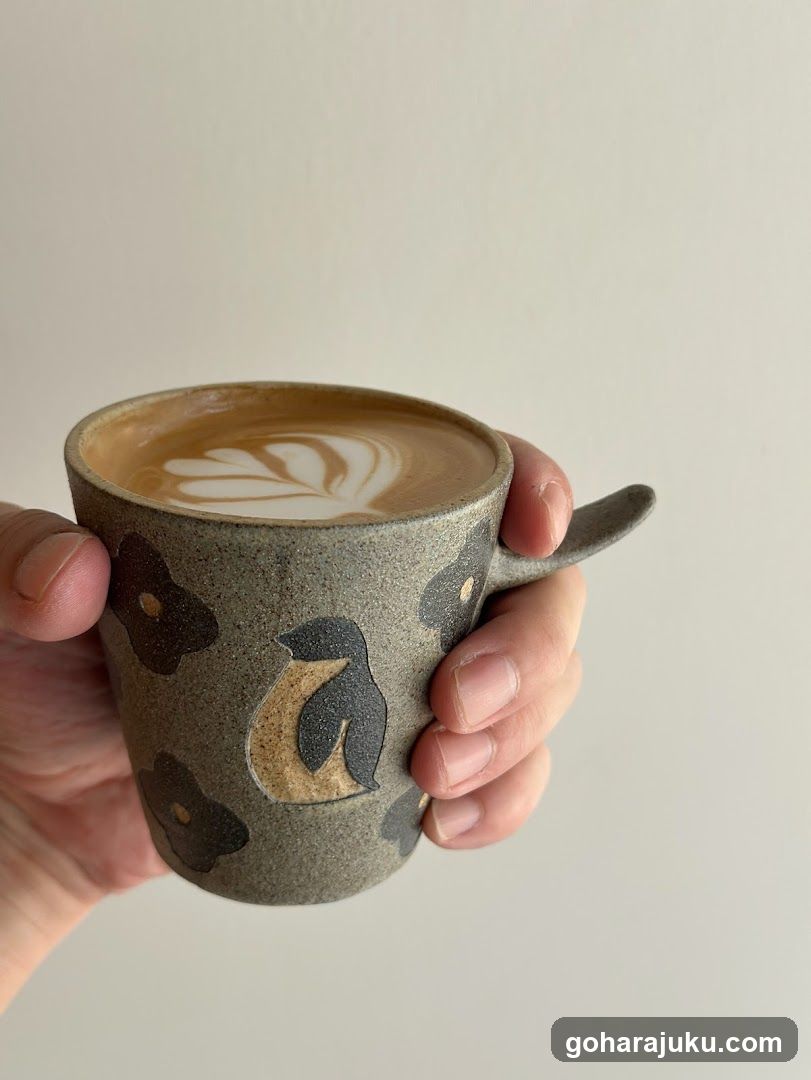 Hand holding ceramic coffee cup with latte art