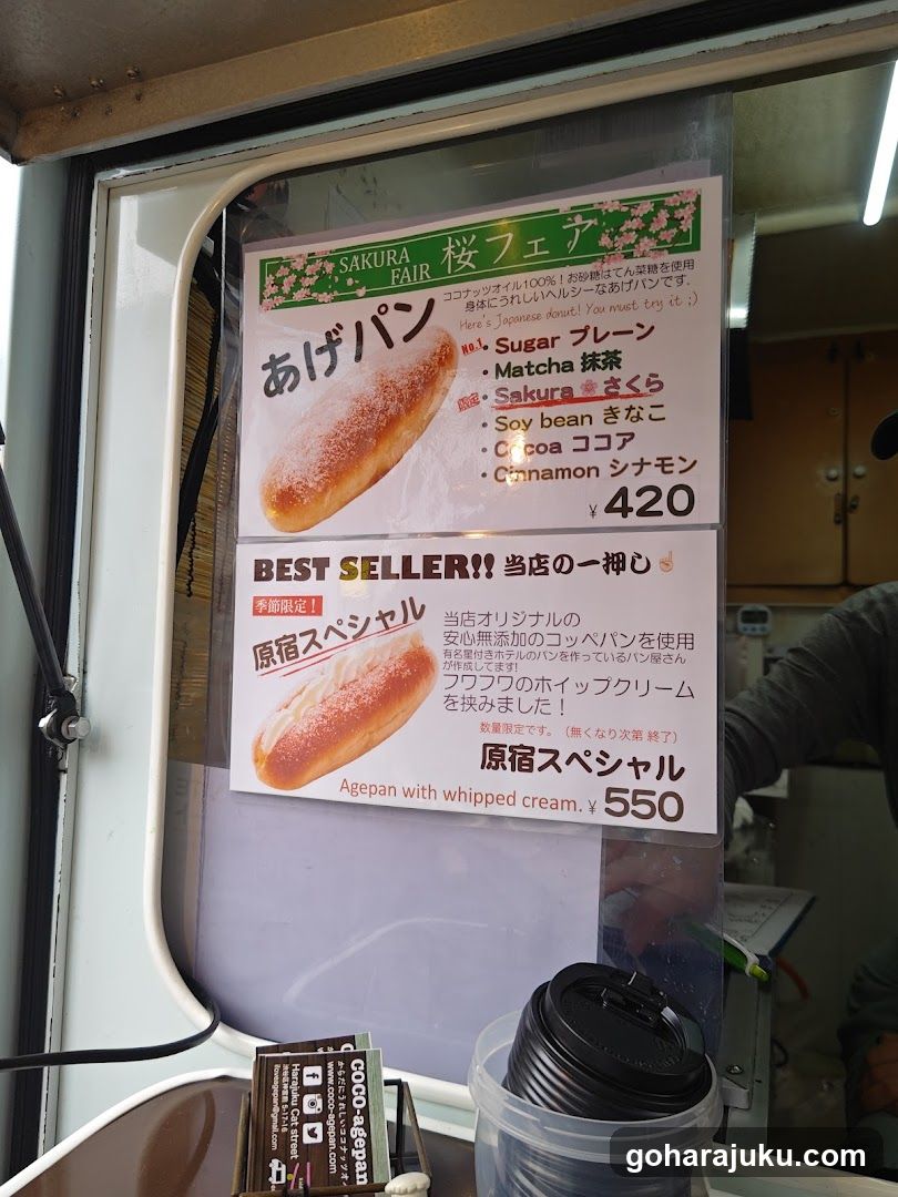 A close-up of a menu board inside a food truck or shop window, featuring two main items with prices and flavor options.