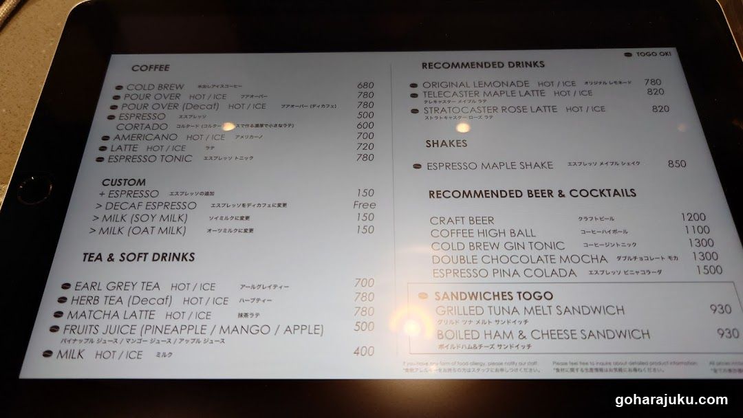 A printed menu on a tablet screen showing coffee, tea, shakes, beer/cocktails, sandwiches, and recommended drinks with prices in yen.