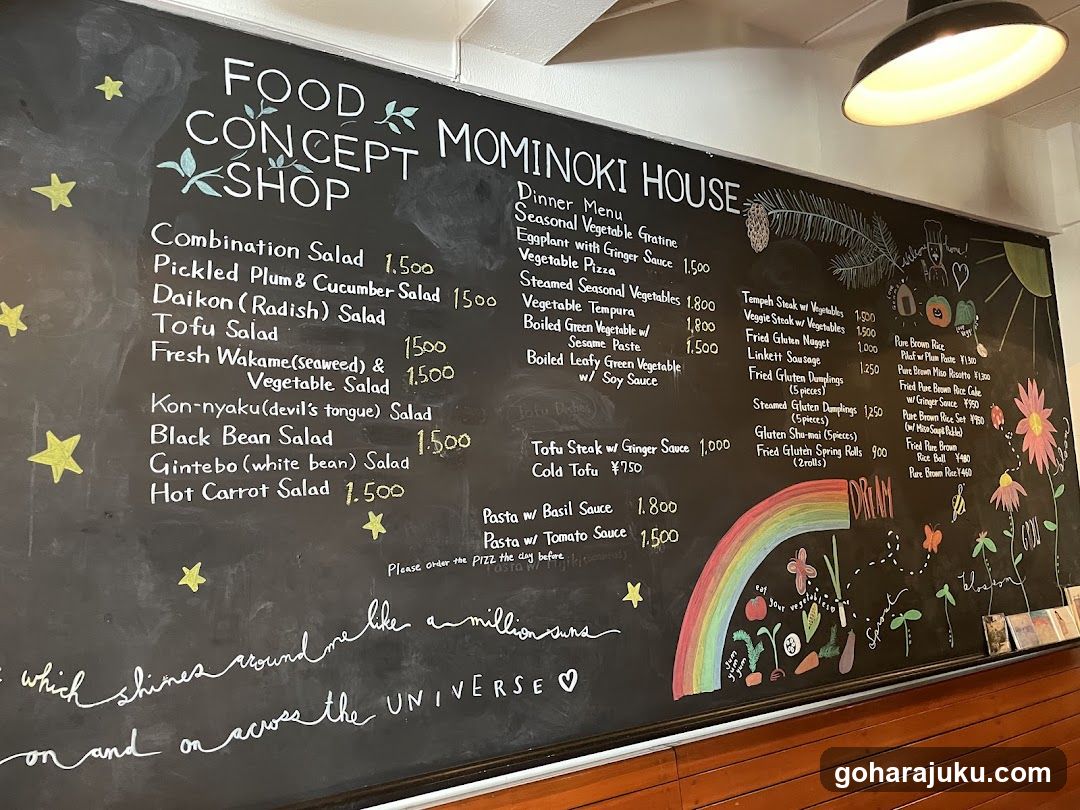 A chalkboard menu board displaying a variety of Japanese-style salads and dishes with prices.