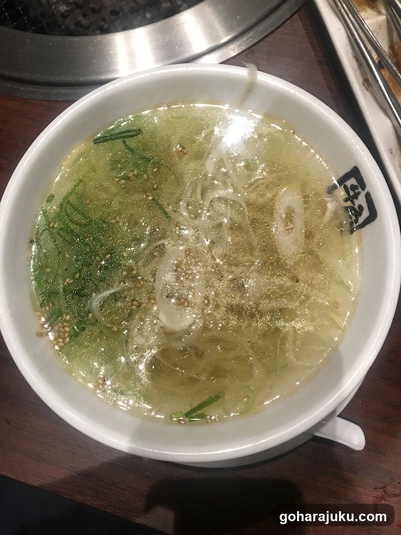 Bowl of clear soup with herbs and seeds