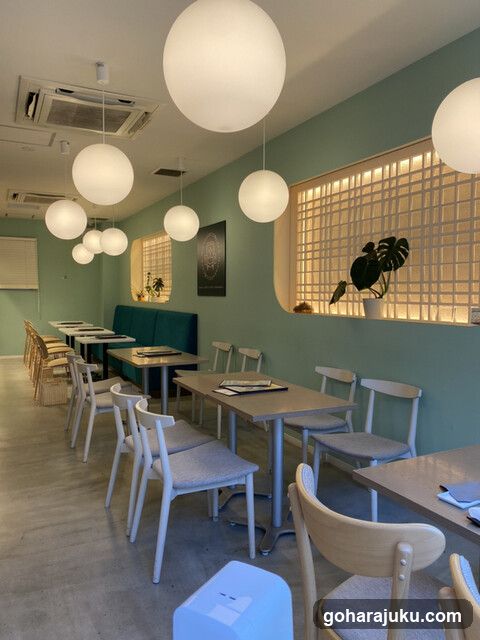 Interior of a modern café with teal walls and spherical pendant lights.